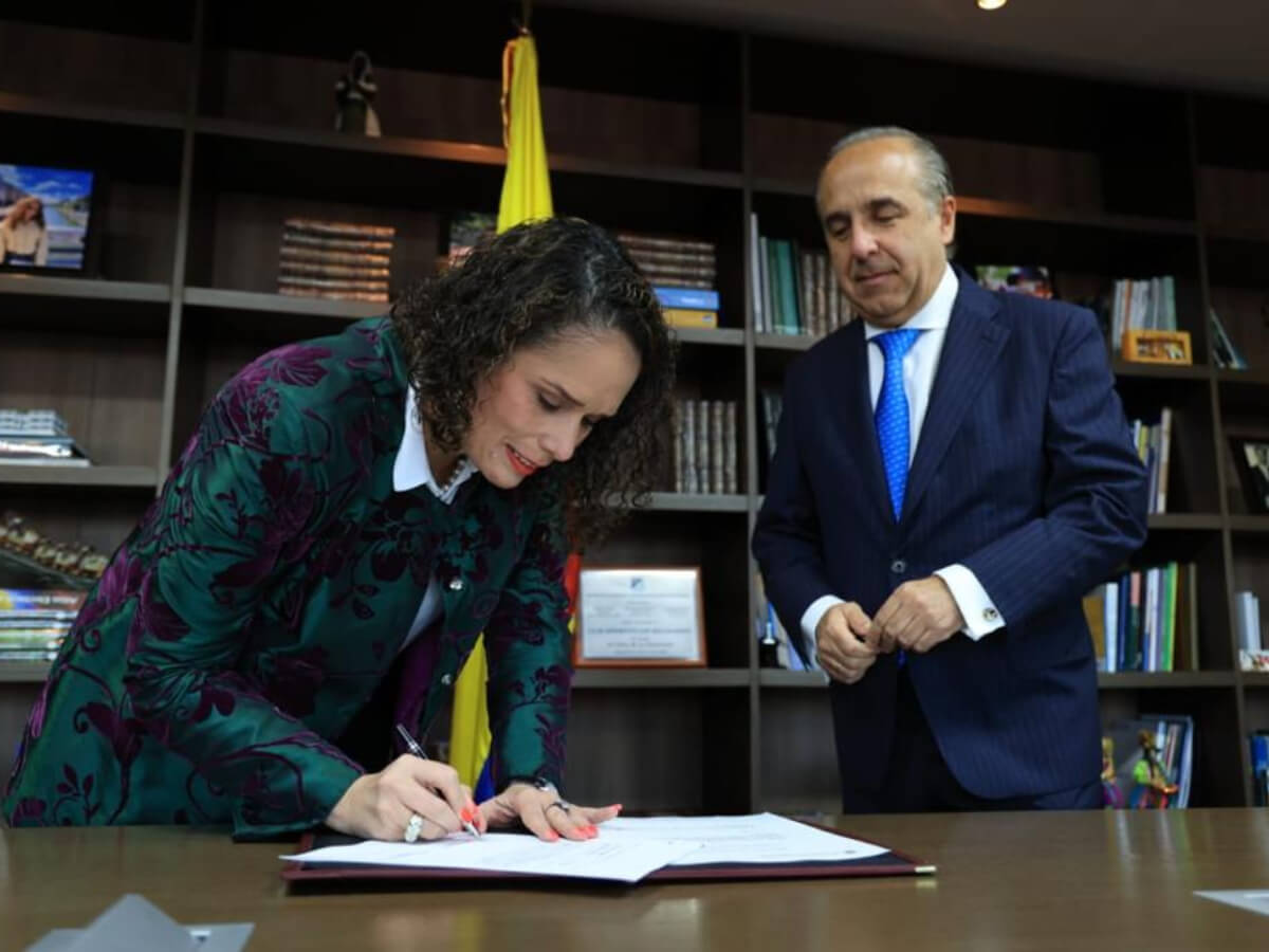 María García firmando un documento acompañada del exministro de Transporte William Camargo